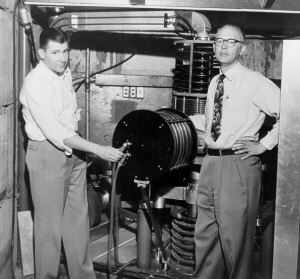 Physicists David Nicodemus and Richard Dempster posing with the college's cyclotron, ca. 1954.