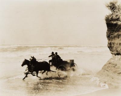 A wagon being driven through the surf on the Oregon coast, ca 1910s.