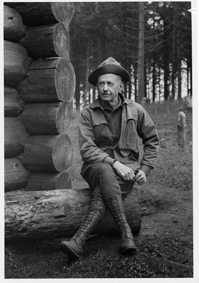 Black and white photograph of George Wilcox Peavy sitting on a log.
