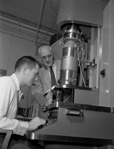 Black and white photograph of Francois Archibald Gilfillan examining an electron microscope.